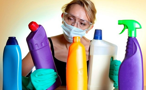 женщина в медицинской маске и резиновых перчатках выбирает средство для чистки ржавчины