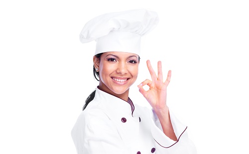девушка шеф повар в поварской одежде улыбается и показывает окей