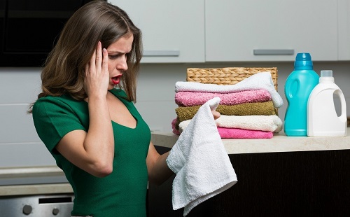 девушка в зеленом платье смотри на пятна на полотенце после стирки в стиральной машике